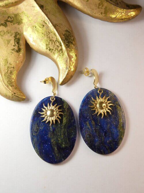 Boucles d'oreilles lune et soleil sur pendentif ovale bleu nuit à paillettes. Bijou Sophia Célesta