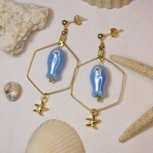 Boucles d'oreilles hexagonales dorées avec petit poisson en céramique bleue et étoile de mer dorée. Bijou en exemplaire unique Sophia Célesta