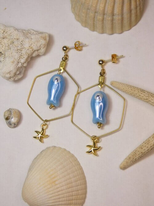 Boucles d'oreilles hexagonales dorées avec petit poisson en céramique bleue et étoile de mer dorée. Bijou en exemplaire unique Sophia Célesta