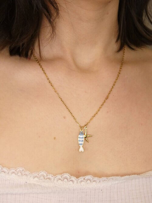 Collier en acier inoxydable doré avec pendentif poisson en résine bleue et blanche et étoile de mer dorée. Collier réversible. Bijou en exemplaire unique Sophia Célesta