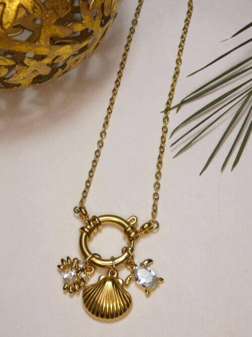 Collier doré avec attache bouée devant à laquelle sont suspendus une breloque crabe, une en forme de coquillage et la dernière en forme de tortue. Bijou en exemplaire unique Sophia Célesta